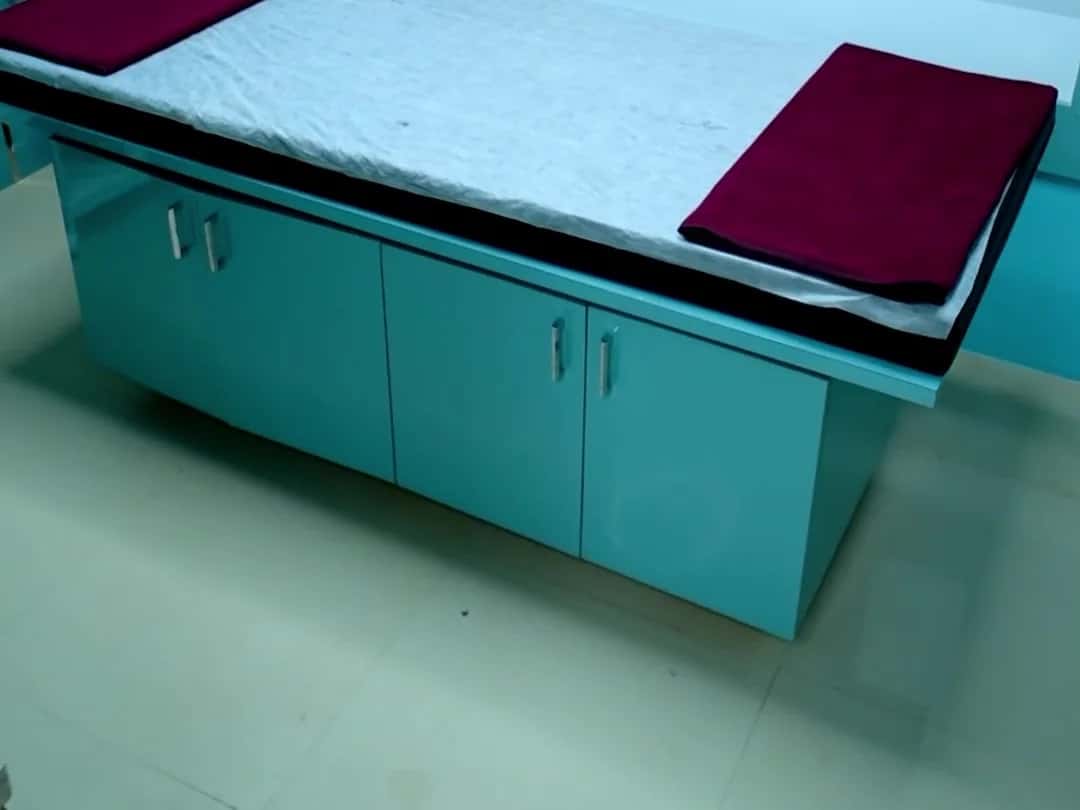 Facial treatment bed with a hydra facial machine and a hair poster on the wall at Scissors Professionals Kolapakkam