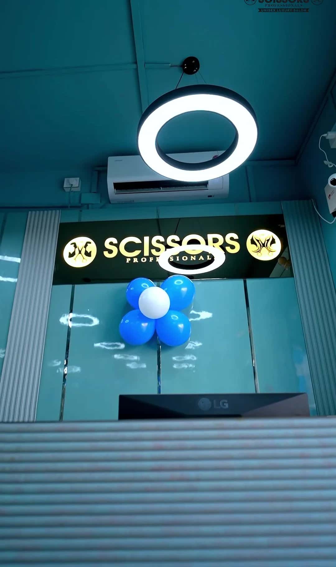 Illuminated Scissors Professionals sign with a blue balloon cluster above the reception desk