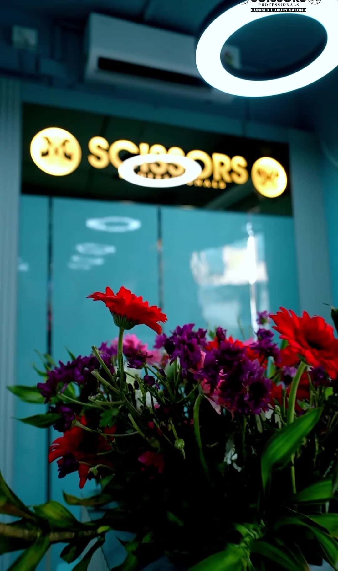 Fresh red and purple flowers at reception beneath the illuminated Scissors Professionals sign