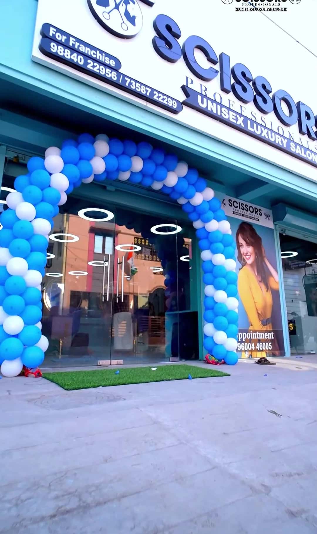 Angled view of the Scissors Professionals Unisex Luxury Salon signboard above the glass entrance and balloon arch