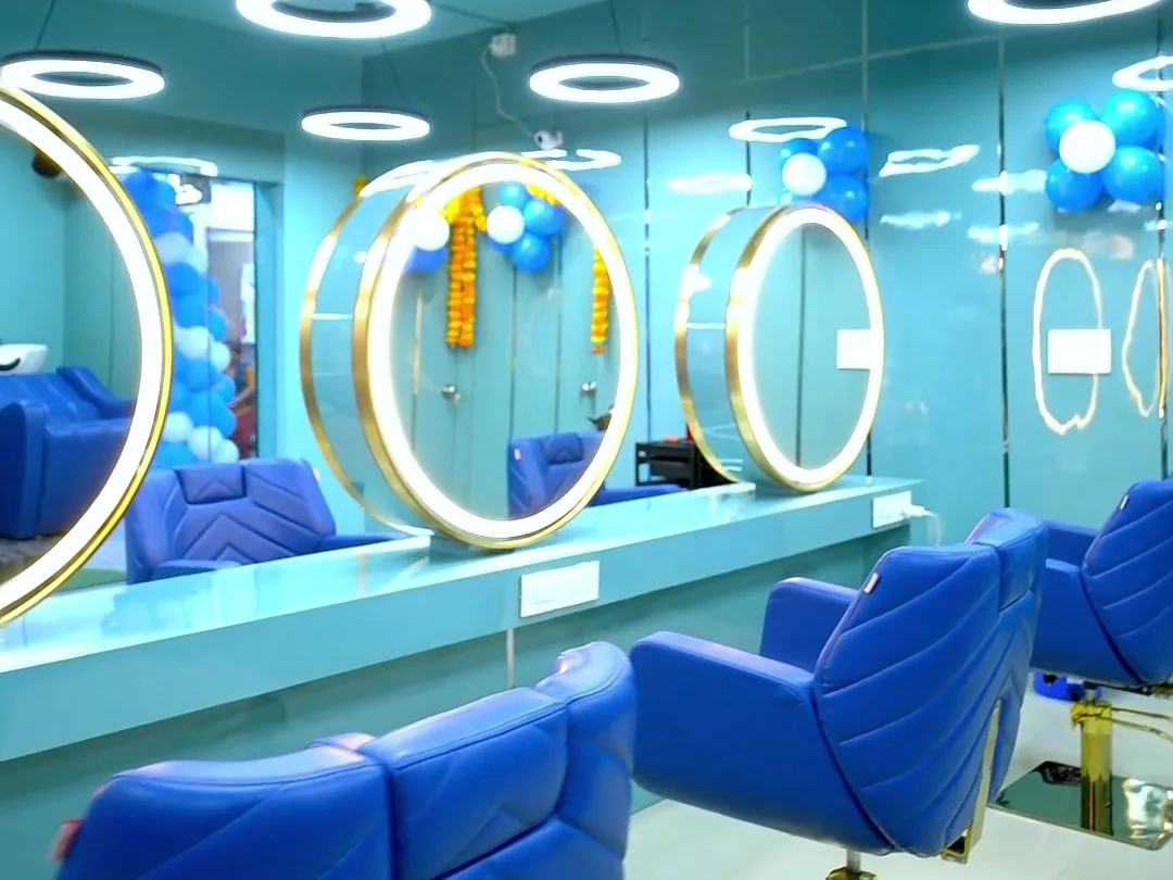Gold ring mirrors, royal blue styling chairs and ring pendant lights across the salon floor